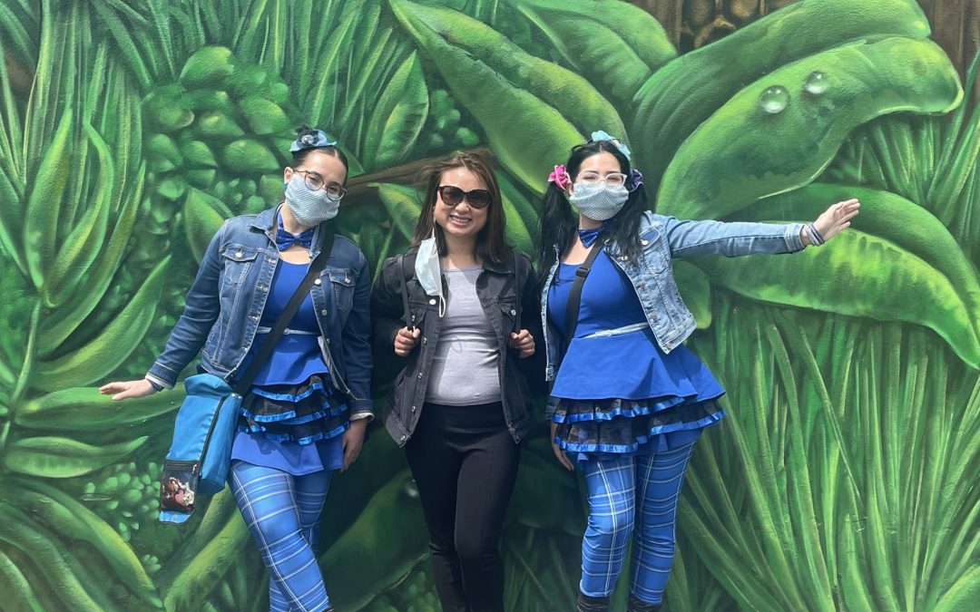 A woman standing with 2 female balloon twisters
