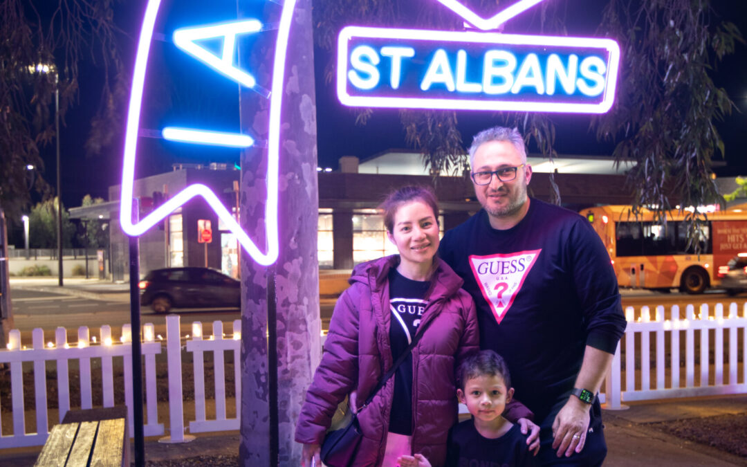 Woman, man & child standing near neon light art installation
