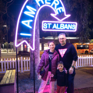 Woman, man & child standing near neon light art installation