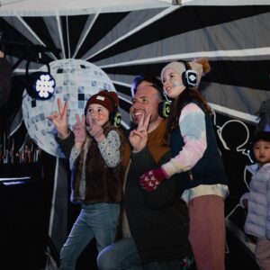 A man posing with two kids at a silent disco