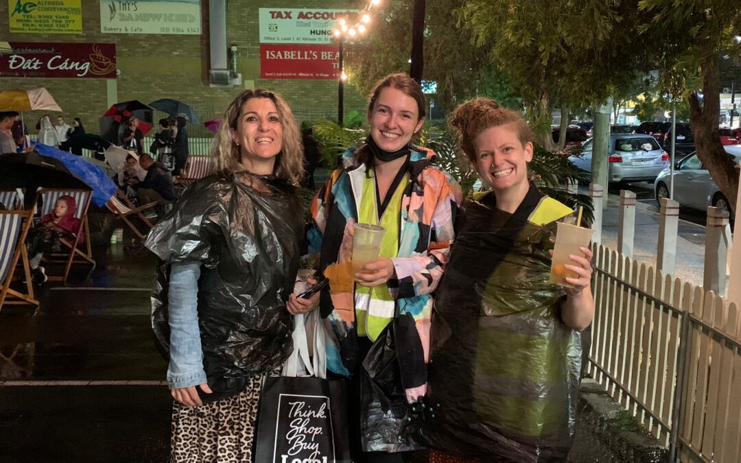 Three women posing on a rainy night in the rain with bubble tea in hand