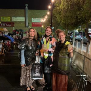Three women posing on a rainy night in the rain with bubble tea in hand